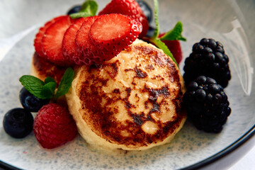 A Delightful Plate of Fluffy Pancakes Topped with Fresh Berries Including Strawberries, Raspberries, and Blueberries, Garnished with Mint Leaves for an Inviting Presentation