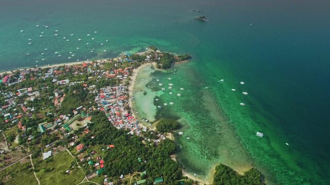Stunning aerial view of Malapascua Island in the Philippines, featuring vibrant coral reefs, crystal-clear turquoise waters, traditional outrigger boats, and coastal houses