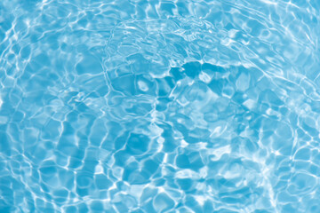 Blue water with ripples on the surface. Defocus blurred transparent blue colored clear calm water surface texture with splashes and bubbles. Water waves with shining pattern texture background.
