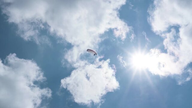 The beauty of paragliding in free flight. Beautiful blue sky on a sunny summer day. View of the paraglider against the blue sky and sun. Cerna Hora in Janskie Lazne.