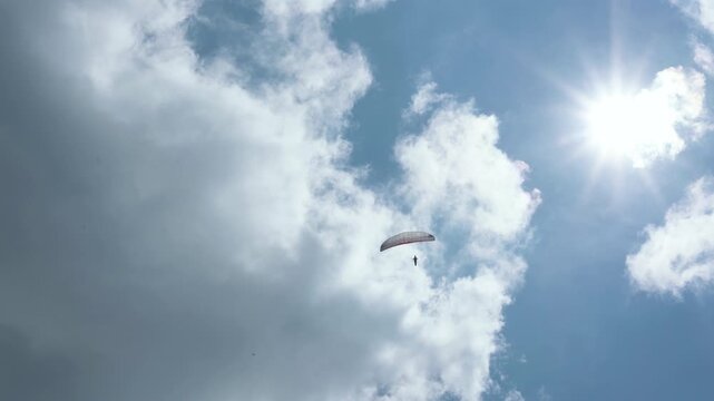 The beauty of paragliding in free flight. Beautiful blue sky on a sunny summer day. View of the paraglider against the blue sky and sun. Cerna Hora in Janskie Lazne.