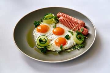 A Delicious Breakfast Platter Featuring Three Perfectly Cooked Eggs, Juicy Sausages, Fresh Herbs, and Delightfully Spiraled Cucumbers on a Modern Plate