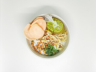 Top-down view of a savory Asian rice porridge bowl with various toppings on a clean white...