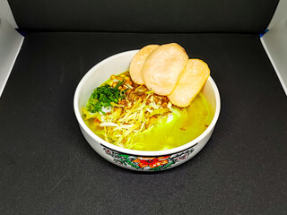 A hearty bowl of Soto Ayam, a classic Indonesian yellow chicken soup with crackers