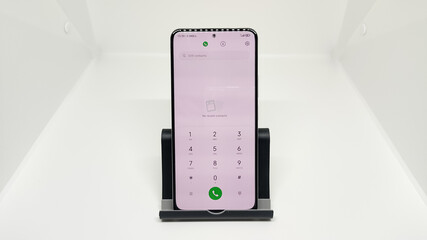 Modern smartphone on a stand with the dialer app open on a white background
