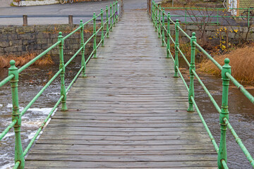 Old Wooden Bridge With Iron Fence for Pedestrians Over Small River Stream in Sweden