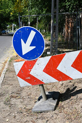 Arrow signs on the street next to a construction site