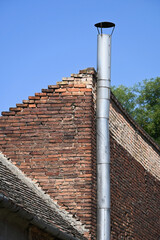 High smoke stack next to a brick wall
