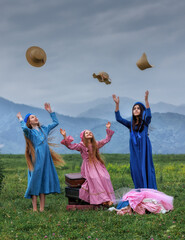Dreamy vintage girl in blue dress reading a book on stacked suitcases in countryside field under cloudy sky