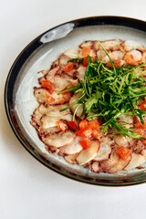 A Gastronomic Exploration of Thinly Sliced Meat Carpaccio Garnished with Fresh Greens and Diced Tomatoes for a Flavorful Culinary Experience