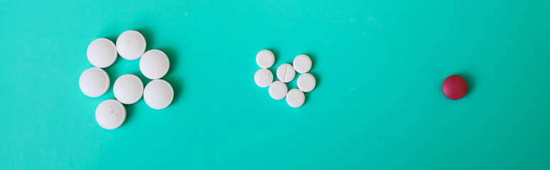 Piles of white pills and one red pill on a vibrant turquoise background create a visual accent....