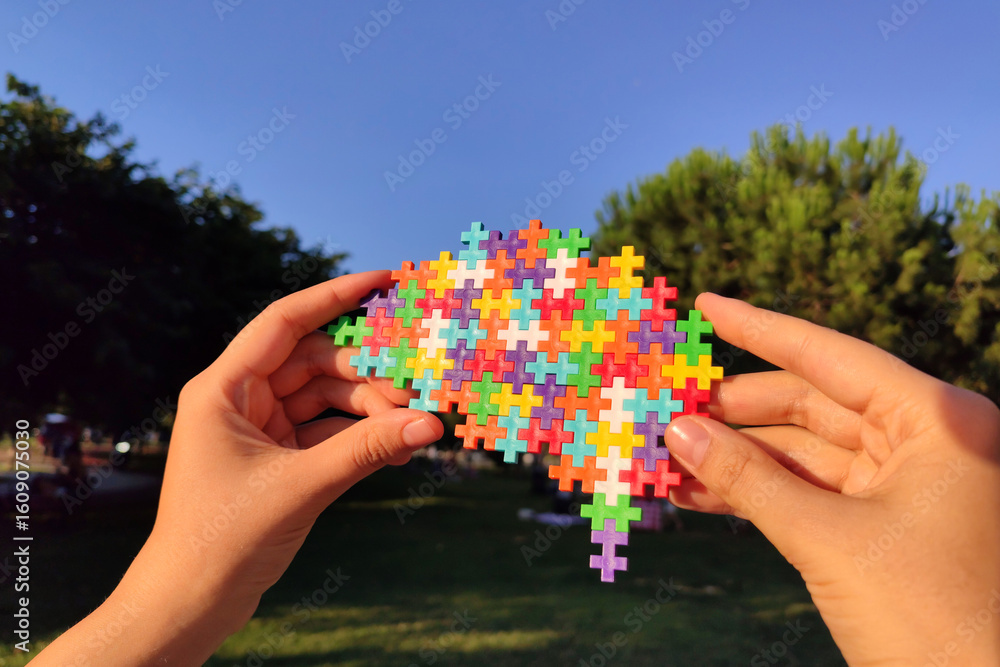 Poster multicolored puzzle in the shape of brain held in hand. mental health and problems with memory. auti