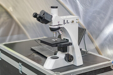 Inverted microscope in a biological research lab, mounted on stand with visible controls Lens and...