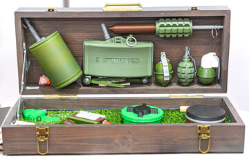 Open wooden case with military equipment green metal helmet, grenade, rifle or carbine, magazine,...