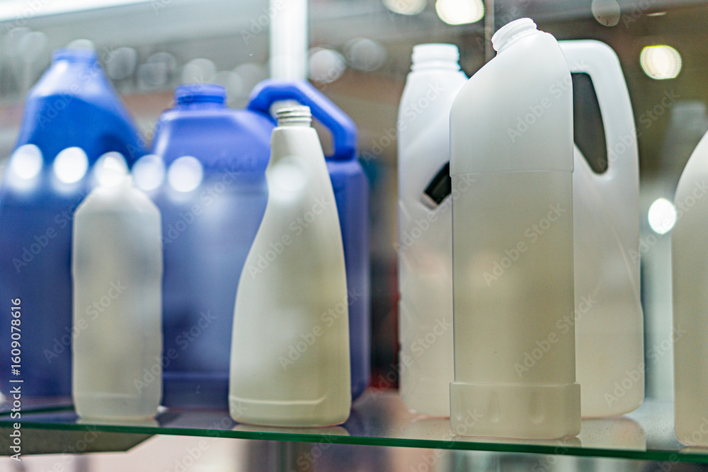 Poster display of plastic bottles on a transparent shelf in an indoor glass case bottles vary in size and c
