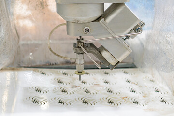 Close-up of an industrial robot in operation, stamping plastic or similar material, against a...
