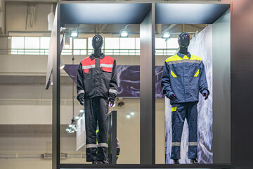 Indoor display of three mannequins in protective suits red white stripes, blue yellow, and black...