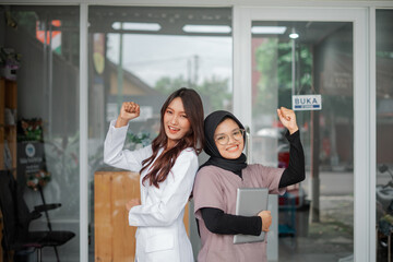 Two Asian confident Female Veterinarians Standing Side by Side in Front of Clinic with one fist...