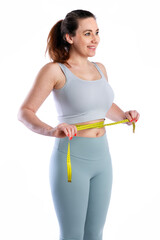 Smiling woman measuring waist with tape in sportswear