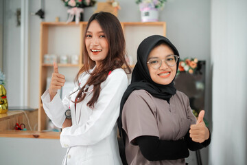 Two Confident Female Veterinarians Standing and Crossing Arms Side by Side while giving Thumbs Up