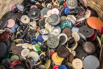 Vintage colorful background of old buttons in grandma's wicker sewing basket. Decorative pattern. Still life of colorful buttons.