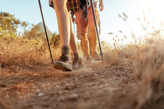 Close up of the hiking boots of a group of young hikers walking on a ridge overlooking a sunset in South Africa