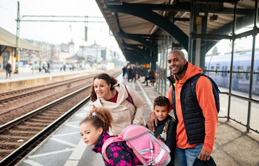Young mixed family traveling and waiting for their train at the train station while on their holiday vacation