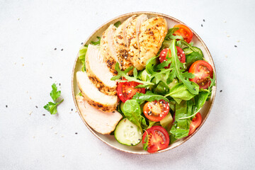 Green salad with grilled chicken meat at black table.