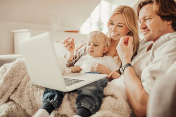 Young family watching a movie on the laptop while eating popcorn