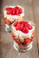 Greek yogurt, granola and strawberry on the rustic background. Selective focus.