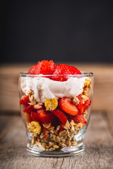 Greek yogurt, granola and strawberry on the rustic background. Selective focus.