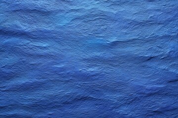 Deep blue textured surface resembling rippling water or heavily grained material with variations in tone and lighting