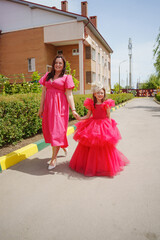 Fototapeta premium Happy well-dressed family on a walk. Mom and little daughter/