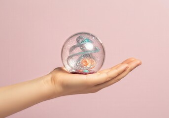 Hand holding creative transparent sensory orb with swirling glitter inside