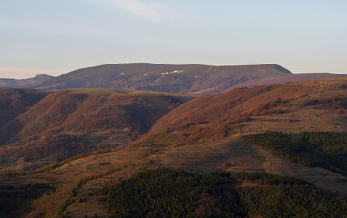 Open landscape photo of brown hills and mountains in the background.
