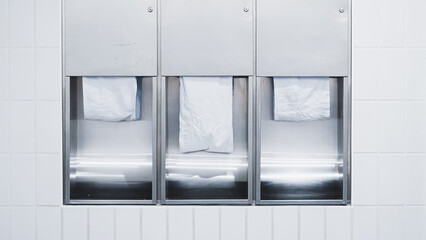 White restroom with three towel holders for hand drying in clean bright setting