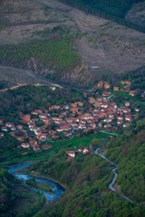 Aerial view of the mountain village. Mountain roads pass through the village and you can see the meanders of the blue mountain river.
