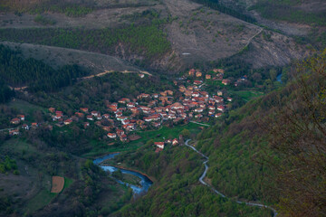 Aerial view of the mountain village. Mountain roads pass through the village and you can see the meanders of the blue mountain river.
