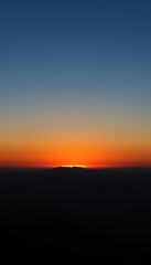 Obraz premium Vibrant sunset behind mountain silhouettes at dusk