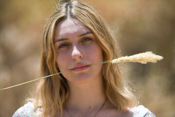 Portrait of a young, beautiful blonde woman on a sunny summer day, holding a dry, soft ear of corn...