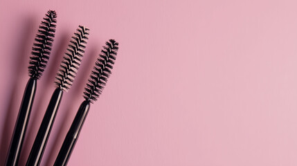 Close-up of professional brushes for eyebrow and eyelash extensions arranged on a soft pink background — with copy space for branding or beauty tutorials.

