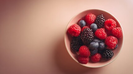 Bowl of mixed berries on blush-beige gradient backdrop softly illuminated