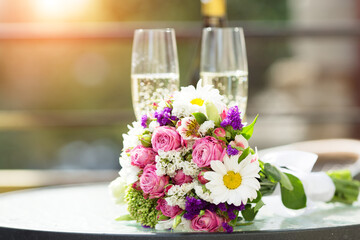 Two glasses of champagne and a bouquet of flowers against the background of the evening sky at...
