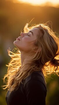 Serene Moment of Reflection: A young woman embraces the golden hour, her face turned towards the sun, capturing the peace and tranquility of a moment.