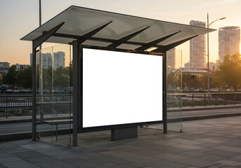 Obraz premium Blank white billboard mockup at a modern bus stop shelter in the city at sunset.