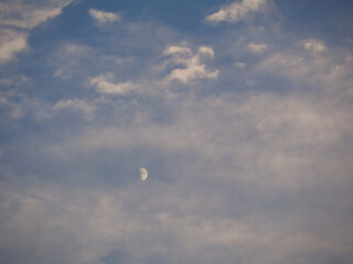 half moon mixed in clouds during day