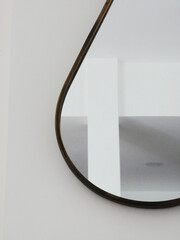 Detail of a design mirror on a wall in a white bright living room