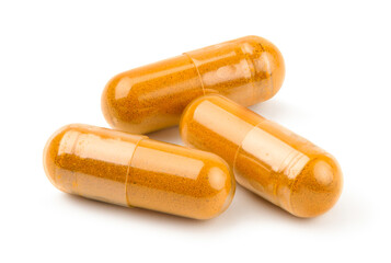 Dried turmeric powder capsules isolated on white.
