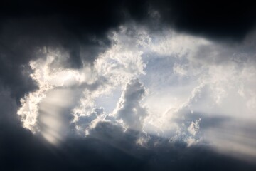 Sunbeams filtering through dark clouds illuminating the sky