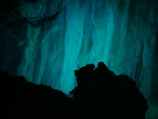 magic light in a cave illuminating the stone wall with mystic bright neon light and a stone silhouette
